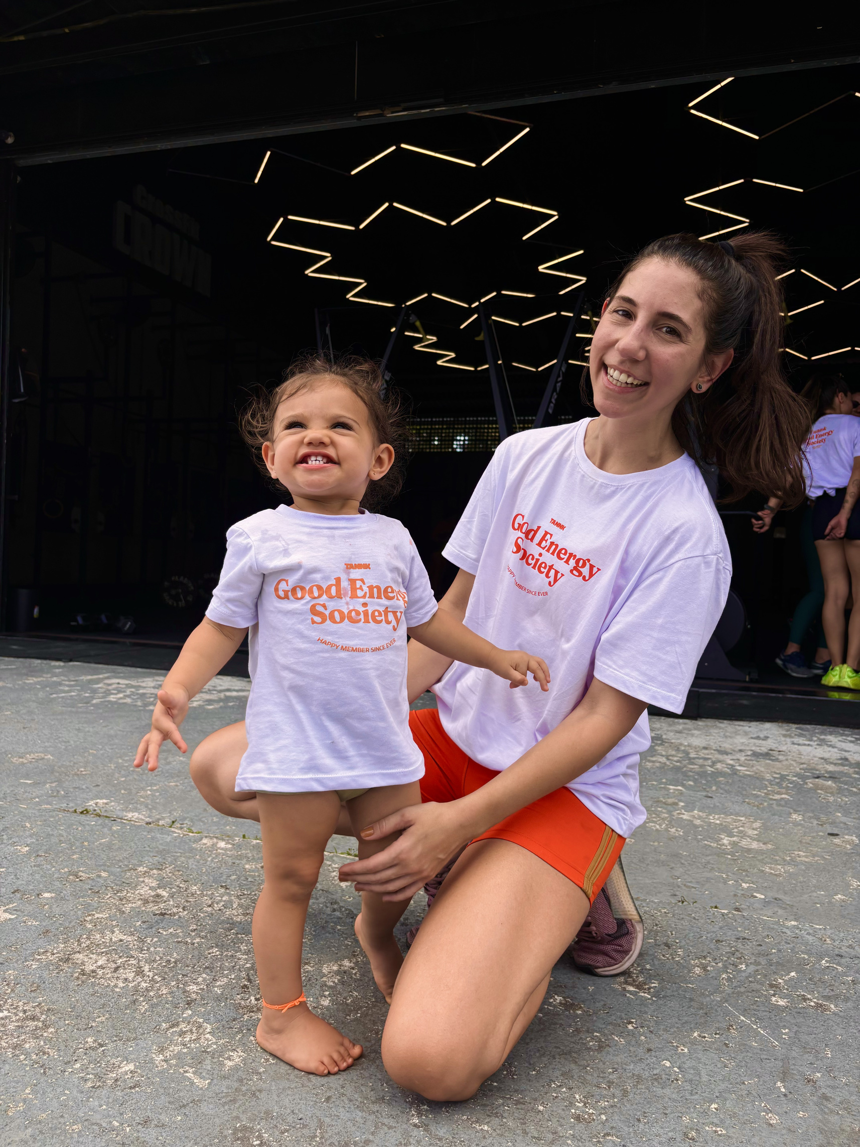 Carol Calmon, fundadora da TANNK, vestindo a camiseta Good Energy Society ao lado de sua filha